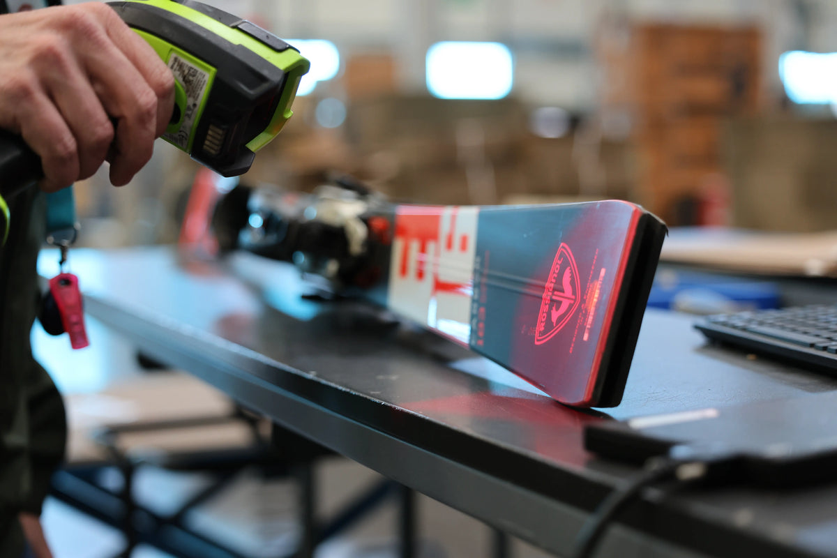Opérateur logistique ReGNR scannant une paire de skis Rossignol pour le contrôle et l'intégration des stocks WMS